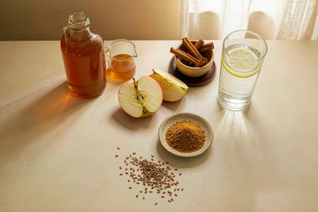 Apple cider vinegar for blood sugar: amber vinegar bottle, halved apple, cinnamon sticks, golden powder dish, glass of water